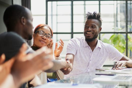 team of young african people in the office shaking hands