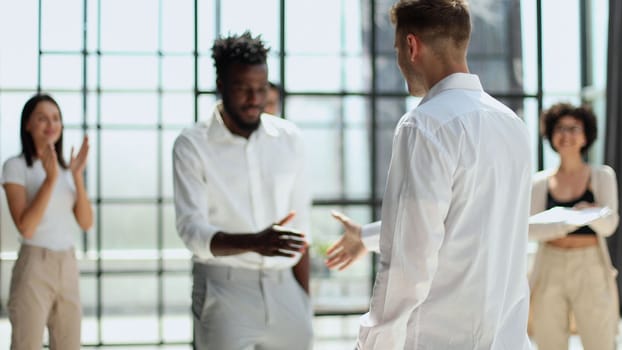 Glad to work with you. Young modern men in smart casual wear shaking hands and smiling while working in the creative office