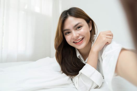 Beautiful young asian woman smiling sitting relax on the bed in the morning, girl using mobile smart phone talking enjoy, communication and social network concept...