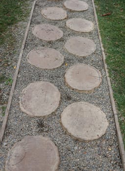 Path of plated stones on gravel bed. Garden architecture, pathway accessory to garden pond. Stone walkway winding in garden