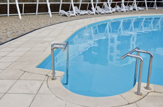 Swimming pool with stairs and ceramic deck in the hotel