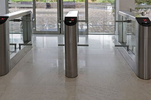 Electronic turnstile. Access system to the building. Security systems for rooms. Several turnstiles are installed nearby. Passage is closed, the concept. Turnstiles are closed, chrome turnstiles with red signal.