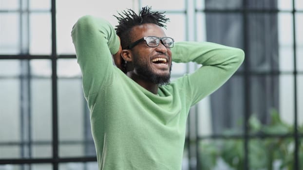 a young man in a green sweatshirt clasped his hands behind his head.