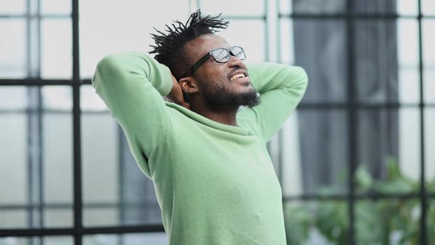 a young man in a green sweatshirt clasped his hands behind his head.