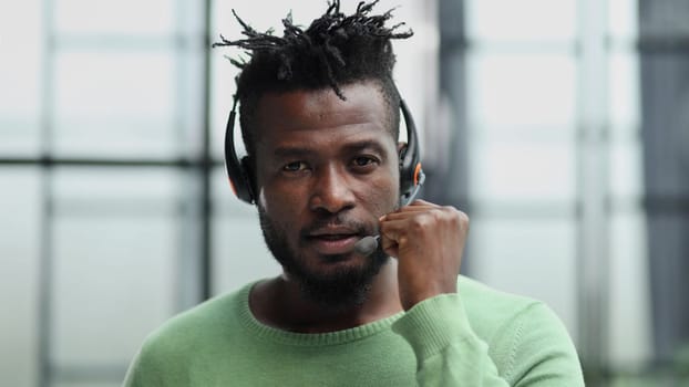 Operator of hot line. Portrait of cheerful african customer service representative with headset in call center, empty space