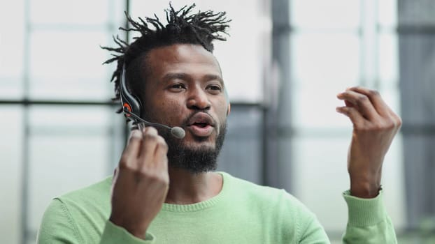 Operator of hot line. Portrait of cheerful african customer service representative with headset in call center, empty space