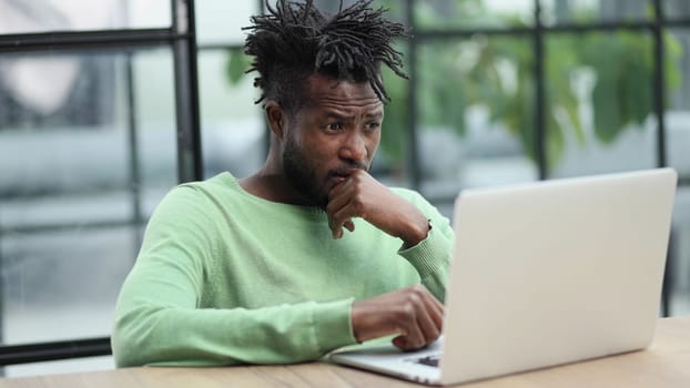 Close-up of a laughing african american man looking into a laptop