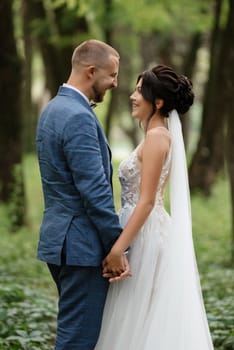 wedding walk of the bride and groom in the deciduous forest in summer