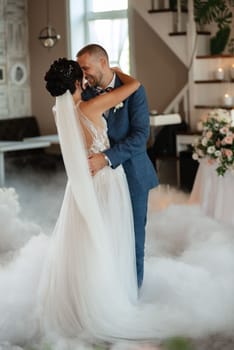 the first dance of the bride and groom inside a restaurant with heavy smoke