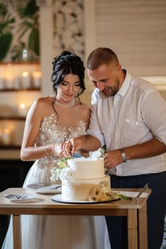 newlyweds happily cut, laugh and taste the wedding cake