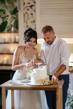 newlyweds happily cut, laugh and taste the wedding cake