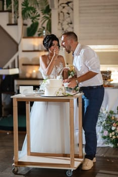 newlyweds happily cut, laugh and taste the wedding cake