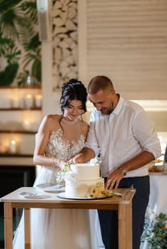 newlyweds happily cut, laugh and taste the wedding cake