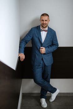 portrait of smiling groom with beard in blue color suit