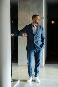 portrait of smiling groom with beard in blue color suit