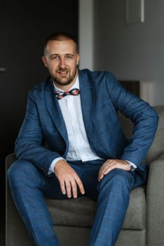 portrait of smiling groom with beard in blue color suit