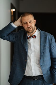 portrait of smiling groom with beard in blue color suit