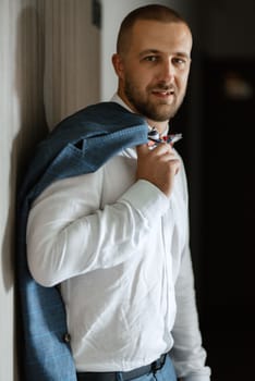 portrait of smiling groom with beard in blue color suit