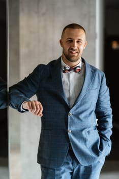 portrait of smiling groom with beard in blue color suit