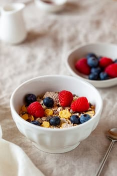 oat flakes breakfast portion with raspberries, blueberries and honey, on the table cloth