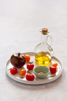 round tray with different tomato varieties, served with salt and olive oil, side view, copy space