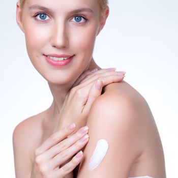 Closeup personable beautiful woman putting skincare moisturizer cream on her arm looking in camera in isolated background as concept for beauty care treatment. Female model applying lotion on her body