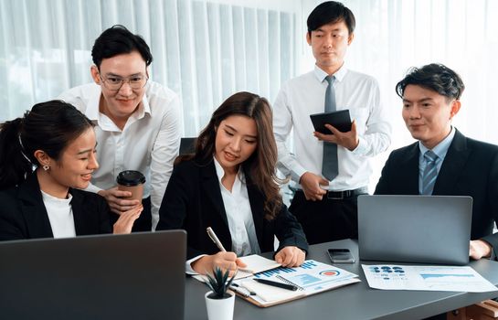 Harmony in office concept as business people analyzing dashboard paper together in workplace. Young colleagues give ideas at manager desk for discussion or strategy planning about project.