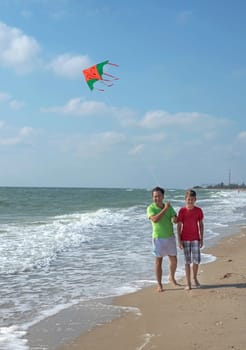 Rest of parents with children. Dad and son fly a kite near the sea