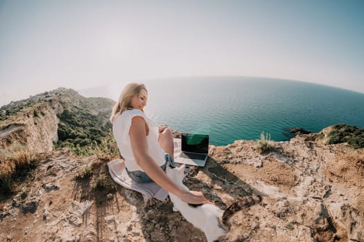 Woman sea laptop. Business woman in yellow hat working on laptop by sea. Close up on hands of pretty lady typing on computer outdoors summer day. Freelance, digital nomad, travel and holidays concept.