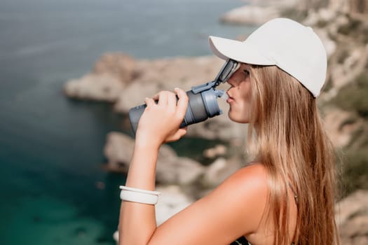 Woman travel sea. Happy tourist taking picture outdoors for memories. Woman traveler looks at the edge of the cliff on the sea bay of mountains, sharing travel adventure journey.