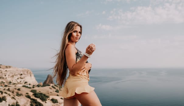 Woman travel sea. Happy tourist taking picture outdoors for memories. Woman traveler looks at the edge of the cliff on the sea bay of mountains, sharing travel adventure journey.