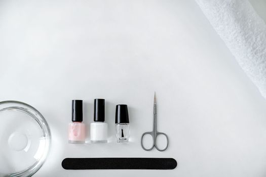 Concept of nail care, set of accessories for manicure, nail polish, nail file, scissors, towel, on white background, flat lay, top view, copy space