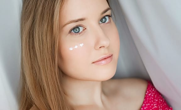 Beautiful woman with skincare cream on her face.
