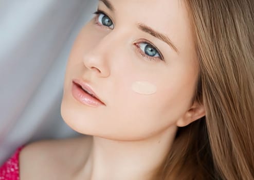 Beautiful woman with liquid make-up foundation on her skin.