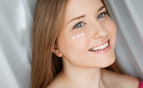 Beautiful woman with skincare cream on her face.