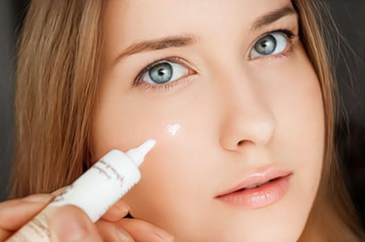 Beautiful woman applying skincare cream on her face.