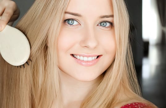 Beautiful happy woman combing her long blond hair.