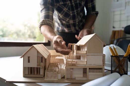 architect working and discussing about an architecture model together with shop drawing paper on table in office.