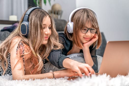 children with wireless headphones on their heads enjoy internet entertainment online on a laptop at home. High quality photo