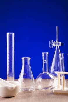 Chemistry lab set on table over blue background. Glassware and biology equipment