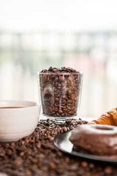 Glass Coffee cup on coffee beans in close up photo. Refreshing beverage in the morning