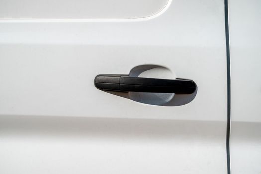 Black handle of sliding door of white colored van