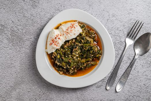 Traditional Turkish spinach meal with rice and minced meat with yogurt on a white porcelain plate