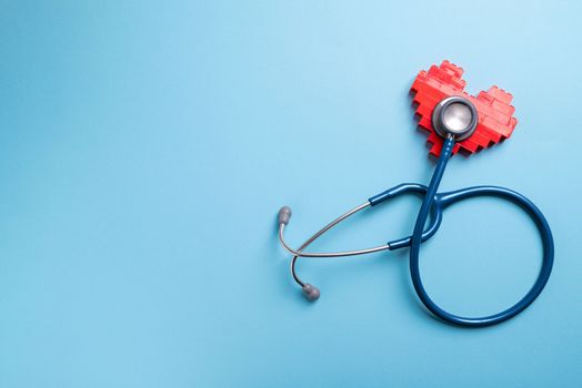 Blue stethoscope standing on red heart on blue background