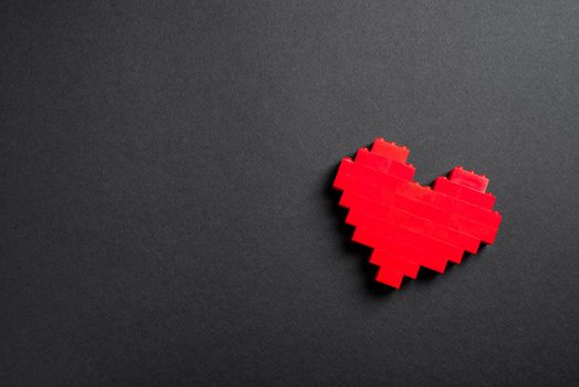 Red heart made of plastic bricks on a dark gray background