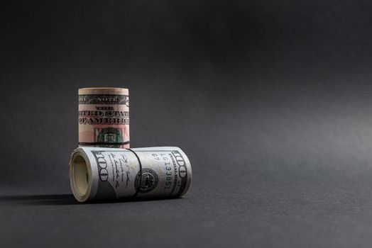 Rolls of 50 and 100 us dollar standing on dark background