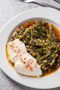 Traditional Turkish spinach meal with rice and minced meat with yogurt on a white porcelain plate