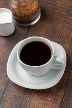 Instant or granulated coffee in white cup on wooden table