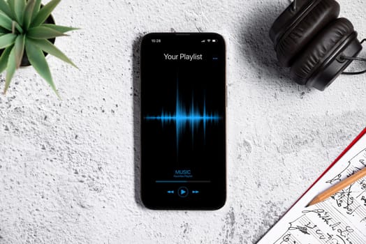 Top view of smartphone with music player app on white stone office desktop