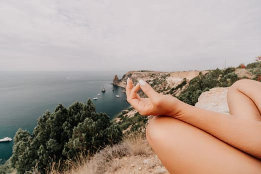 Middle aged well looking woman with black hair doing Pilates with the ring on the yoga mat near the sea on the pebble beach. Female fitness yoga concept. Healthy lifestyle, harmony and meditation.